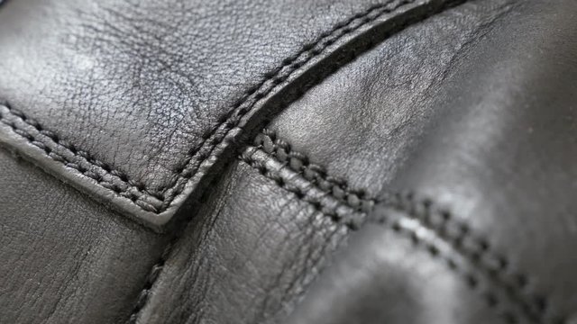 Natural dark leather texture with stitches close-up 4K 2160p 30fps UHD tilting footage - Slow tilt over manufactured leather fabric for jacket or shooes 4K 3840X2160 UltraHD video