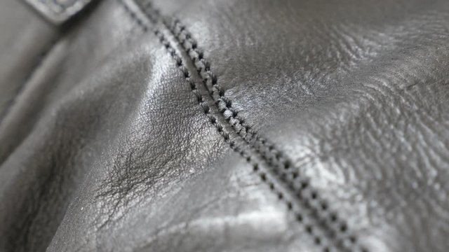 Dark natural leather texture with stitches close-up 4K 2160p 30fps UHD tilting footage - Slow tilt over manufactured leather fabric for jacket or shoes 4K 3840X2160 UltraHD video 