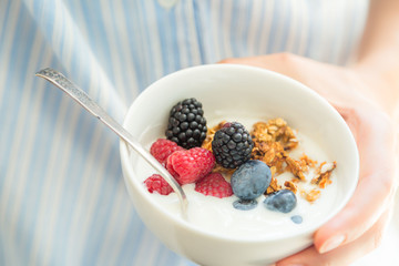 Female holding bowl with yogurt glanola and berries
