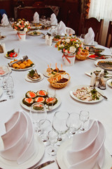 Elegant beautiful decorated table with meals and tableware at wedding reception closeup