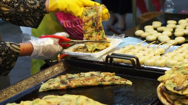 Korean local food, Green onion pancake being cut at street food stall in tourist shopping area