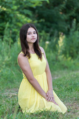 The girl in yellow dress sitting on grass