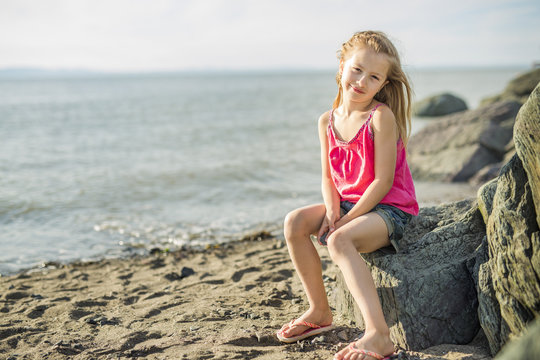 Cute little girl standing close to beach at sunset