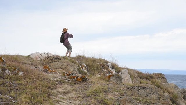 Woman running on the hill near the sea and showing hands up