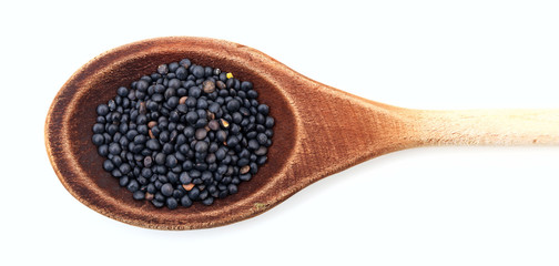 Raw black lentils in a wooden spoon