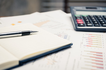 Close up of pen on notepad with business documents and calculator in background.Business concept.