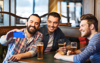 friends taking selfie and drinking beer at bar