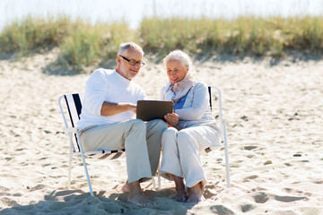 happy senior couple with tablet pc on summer beach