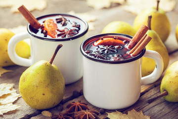 Mulled wine in white rustic mugs with spices and pear fruits. Au