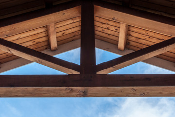 Wooden beam ceiling with symmetrical design. Modern art and design. Interior design with wood detail. Abstract minimal art. Blue sky background. Artistic design. geometrical balance and design.