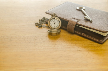 brown leather organizer with key and pocket watch
