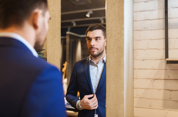 man trying jacket on at mirror in clothing store