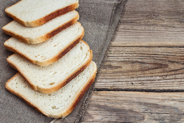 Pieces of white bread on sacking on an old wooden table.