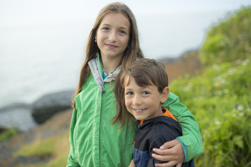 boy and girl having fun on rain close to a sea