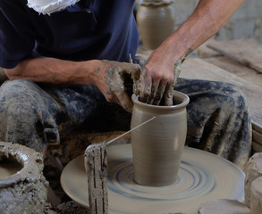 Dirty hands making pottery in clay on wheel