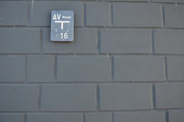 Fototapeta na wymiar gray regular brick wall with water sign