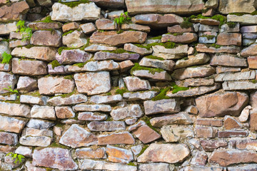 old wall masonry of different sizes with moss