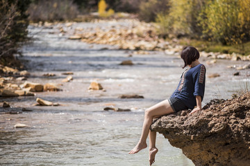 White water Mineral Creek stream in Colorado, USA during the fall with golden aspens and woman on edge dipping feet in water