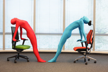 anonymous couple in full body  elastic suits exercising with chairs in office