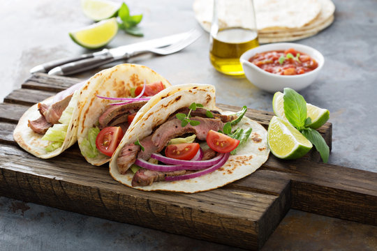 Steak tacos with sliced meet, salad and tomato salsa