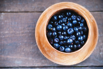 Fresh ripe wild blueberries in a wooden bowl 