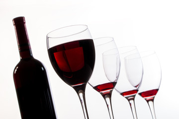 Weinflasche, Weingläser leer und mit Rotwein gefüllt in Reihe und Untersicht, Nahaufnahme
