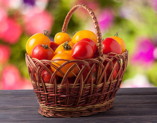 red and yellow tomatoes in a wicker basket on wooden table