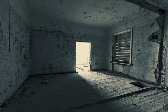 Dark room in an abandoned ruined house. Grunge texture. Tinted photo.