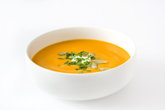 Pumpkin soup with cream and pumpkin seeds isolated on white background

