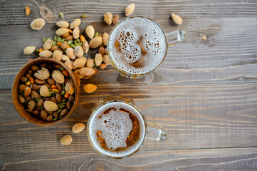 Two Oktoberfest beers with pistachio nuts on a wooden table, top view