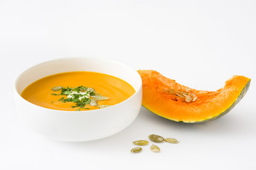 Pumpkin soup with cream and pumpkin seeds isolated on white background

