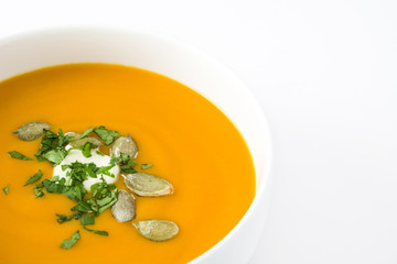Pumpkin soup with cream and pumpkin seeds isolated on white background


