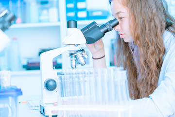Young woman student work in microbiological laboratory with microscope