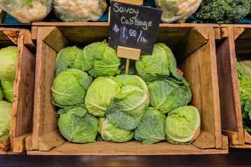 Fresh cabbage vegetable in wooden box stall in greengrocery with price chalkboard label.