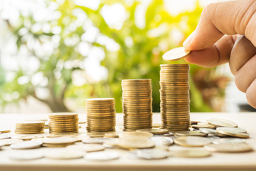 Hand putting money coins stack growing with green and sunlight b