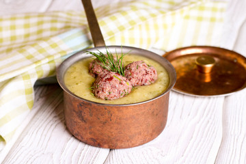 Zucchini soup close-up in saucepan and meatballs