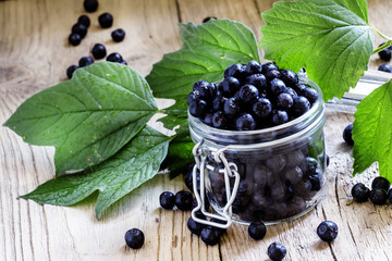 Fresh berries chokeberry in a glass jar, vintage wooden backgrou