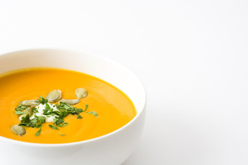 Pumpkin soup with cream and pumpkin seeds isolated on white background
