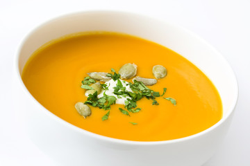 Pumpkin soup with cream and pumpkin seeds isolated on white background
