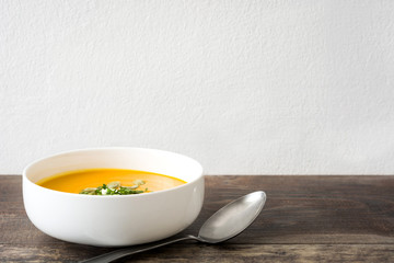 Pumpkin soup with cream and pumpkin seeds on wooden background

