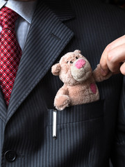 The elegant stylish businessman keeping cute teddy bear in a his breast suit pocket. Formal negotiations concept.
