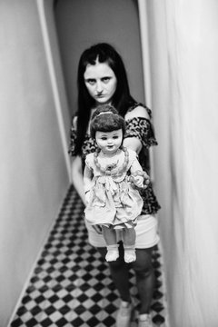 Scary woman showing doll at camera