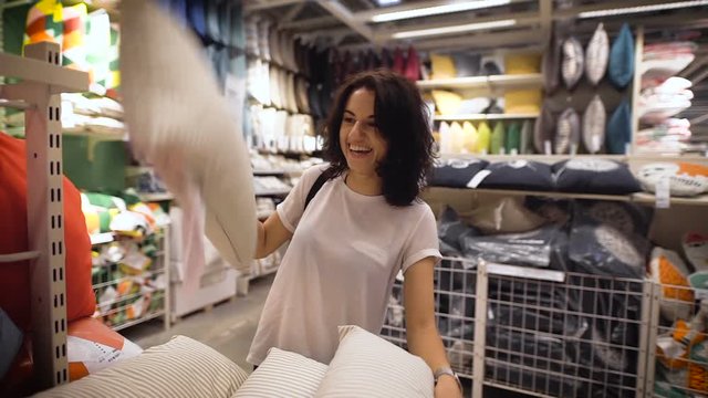 Pretty, young woman choosing a pillow