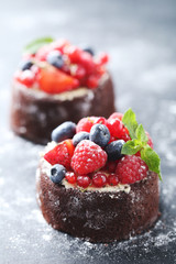 Sweet chocolate cakes with berries on black wooden table