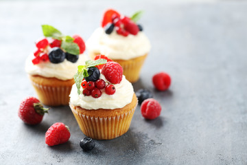 Tasty cupcakes with berries on grey table