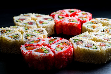 Japanese rolls with fish on a black background