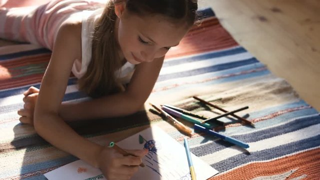 Pretty little girl drawing with color pencils on a floor in her nursery room