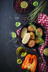 Fototapeta na wymiar Young ripe potatoes in a black cast iron pan with herbs, olive oil, rosemary, pepper, sea salt for baking. Healthy homemade food, Vegetarian and diet.