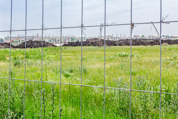 Obraz premium View on the construction site through a fence wire