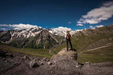 Hiker with backpack standing on top of a mountain and enjoying valley view/ Panoramic view